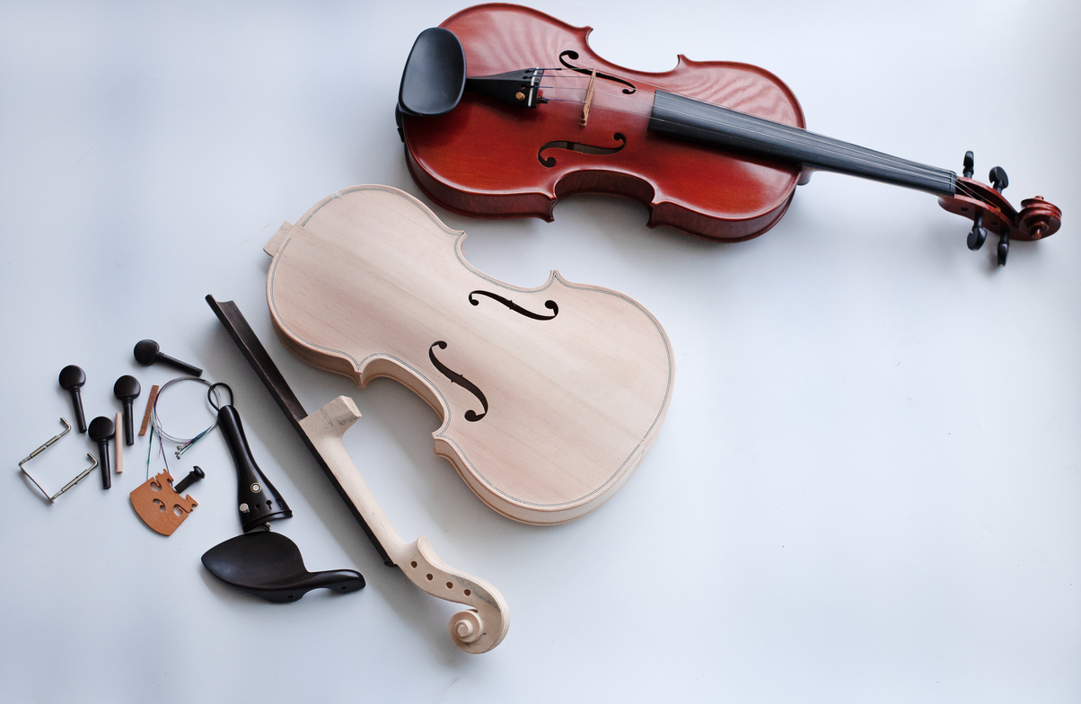 The raw violin and accessory put beside completed violin on white background